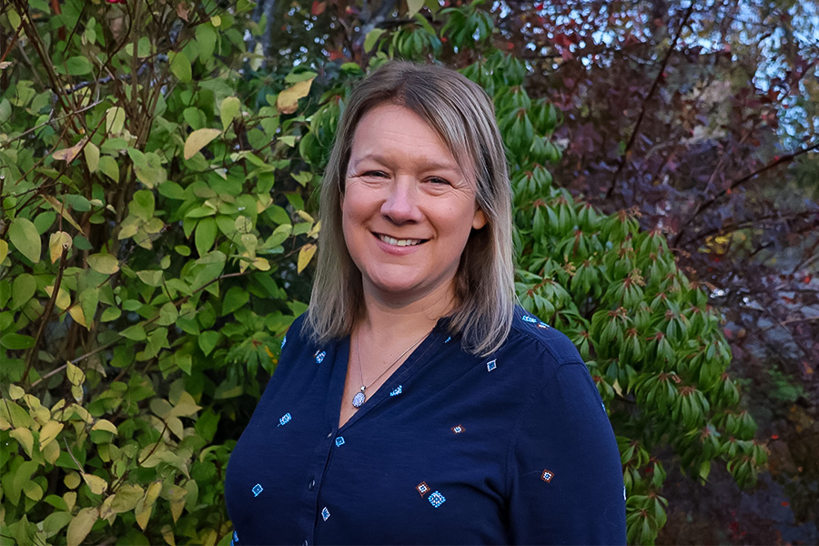 Monica standing infront of some green hedges